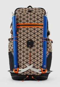 Zaino con motivo geometrico in beige e nero, con aste blu e finiture in argento, dettagli arancioni e una finitura testurizzata.