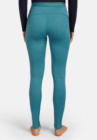 Tealfärgade leggings gjorda av ett mjukt, elastiskt tyg med hög midja och sömlös design, med en åtsittande silhuett.