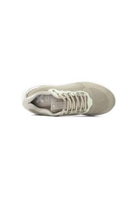 Zapatilla deportiva beige con parte superior de malla, cierre de cordones, cuello acolchado y suela texturizada. Presenta un logo y un diseño transpirable.