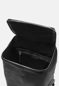 Sac à dos en cuir noir avec fermeture zip, intérieur spacieux, doublure en tissu, poche avant avec zip et texture lisse.