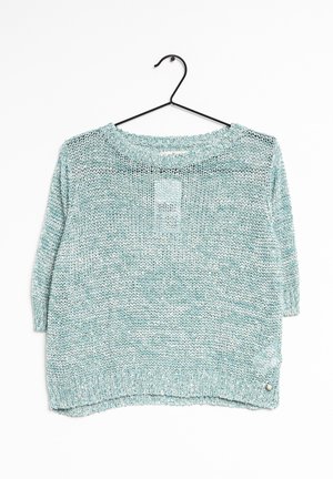 Pull à manches courtes en maille légère bleu clair suspendu sur un cintre noir sur fond blanc.
