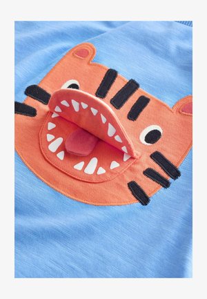 Tessuto blu con il volto di un animale arancione con una bocca che si apre, rivelando una lingua rosa. Sono dettagliate strisce nere e denti bianchi.