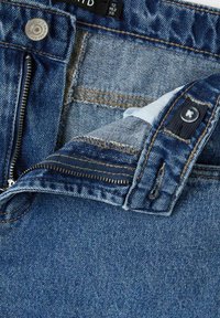 Jeans in denim con un lavaggio blu e cuciture arancioni a contrasto, con zip frontale e chiusura a un bottone. Etichetta interna visibile.