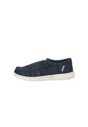 Scarpa casual blu navy slip-on con tomaia in tessuto strutturato, suola bianca screziata e stringhe regolabili con chiusura a scatto nera su sfondo bianco.
