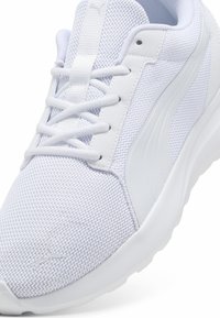 White athletic shoe featuring a mesh upper, textured fabric, flat laces, and a smooth, rubber sole with a subtle logo detail on the side.