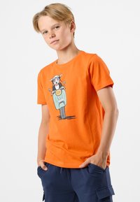 Orange bomulds-t-shirt med et grafisk motiv af en hund på en scooter. Korte ærmer, rund halsudskæring og afslappet pasform.
