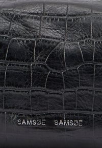 Sort kunstlæder med krokodilletekstur, prydet med præget "SAMSØE SAMSØE" logoer i sølv. Glat finish og rektangulær form.