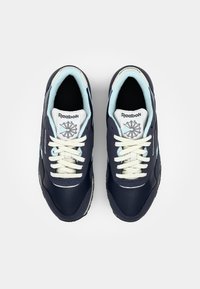 Baskets marine avec des accents bleu clair, dotées d'une tige en textile lisse, de lacets blancs et d'une semelle en caoutchouc. Comprend un logo sur la languette.
