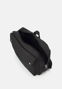 Svart ryggsäck med rektangulär form, gjord av texturerat tyg, med ett dragkedjeöppning och två externa knappar. Inre fack synligt.