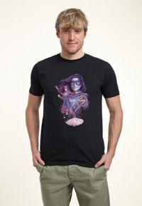 Camiseta negra de algodón con un diseño gráfico colorido de una superheroína en una pose dinámica, con un vibrante fondo púrpura y rosa.