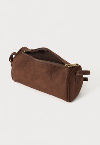 Pocchetto cilindrico in suede marrone con chiusura a zip, caratterizzato da una texture liscia e estremità arrotondate. Piccole finiture in pelle sui lati.