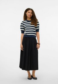 Maglione a righe in navy e bianco, con maniche a palloncino corte, abbinato a una gonna pieghettata nera. Ballerine nere con motivo completano l'outfit.