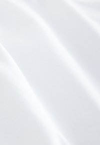 Soft white fabric with smooth folds and subtle texture, showing light and shadow variations on the surface.