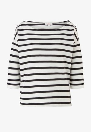Camisa de manga larga a rayas en blanco y negro, combinada con unos vaqueros rasgados azules. Botas negras con cordones completan el conjunto.