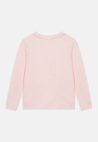 Camicetta a maniche lunghe in cotone rosa soft. Collo a girocollo con una texture morbida. Il retro presenta un piccolo dettaglio ricamato lungo il collo.