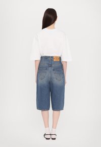 Denim kratke hlače z visokim pasom, svetlo modre pranje in bledenje. Imajo zanke za pas in dva zadnja žepa. V kombinaciji z ohlapnim belim T-shirto.