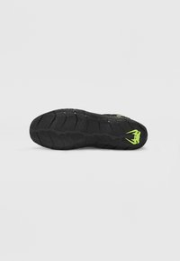 Black athletic shoe sole with a textured grip pattern and a bright green logo. The rear features distinctive tread and slight curvature.