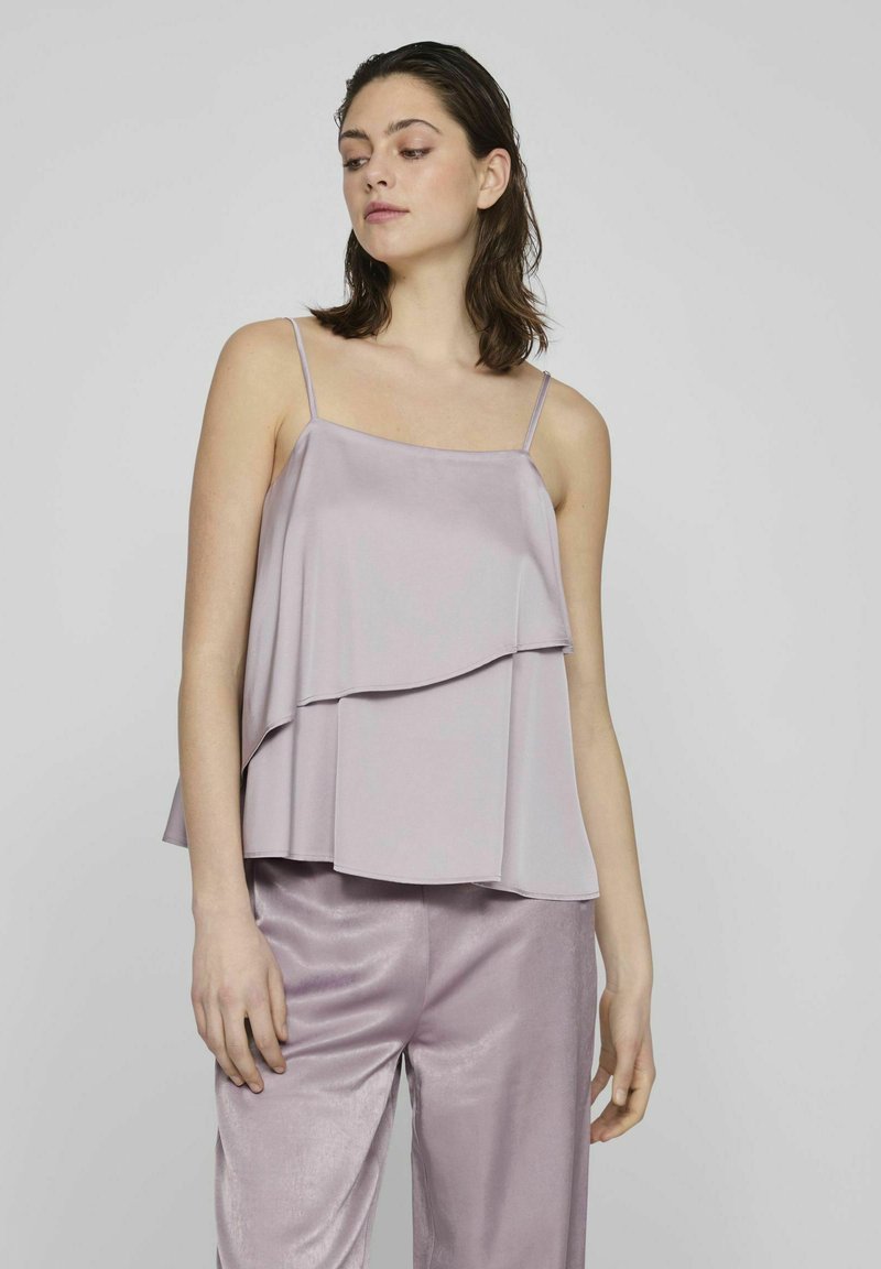 Top de color lavanda con capas y tirantes finos, que presenta una tela suave y fluida con un diseño en escalones delicados, combinado con pantalones de seda a juego.