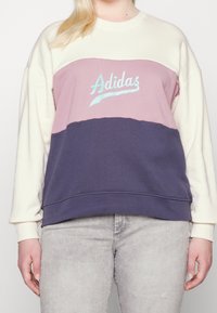 Sudadera con bloques de color púrpura y azul marino con mangas crema, con un logo de Adidas en azul aqua en el pecho. Tela suave, ajuste relajado.