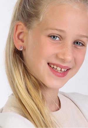 Silberne Hufeisenohrringe mit kleinen funkelnden Akzenten, die an einem hellhäutigen Mädchen mit langen blonden Haaren befestigt sind und lächelt.