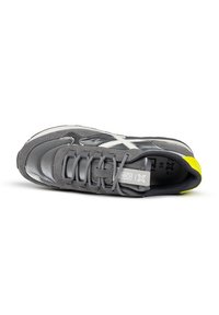 Gray athletic shoe with a mix of smooth and suede textures, accented by a white logo and a bright yellow heel detail. Lace-up design.