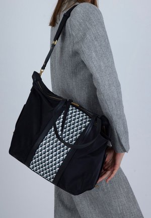 Crna torba od tkanine s geometrijskim uzorkom u sivim i bijelim tonovima, s dvostrukim gornjim ručkama i zatvaračem, naglašena zlatnim detaljima.