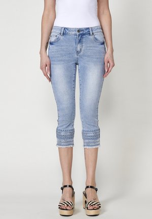Un jeans court bleu clair avec des poignets brodés, des ourlets effilochés, et un design classique à cinq poches. Fabriqué en denim, ajusté à la jambe.