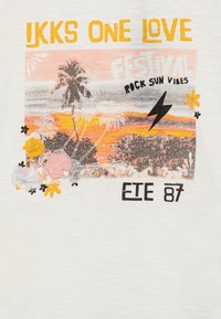 Grafisk t-skjorte med et solnedgangsdesign med palmer og blomster, utsmykket med teksten "JKKS ONE LOVE FESTIVAL" i gult og svart.
