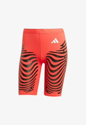 Shorts deportivos rojos hechos de una tela suave con un patrón ondulado negro, con un logo blanco de Adidas en la cinturilla.