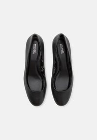 Sorte ballettfutter med en glatt skinnoverdel, rund tå og enkel design. Innvendig har de merket innersåle og diskrete sømdetaljer.