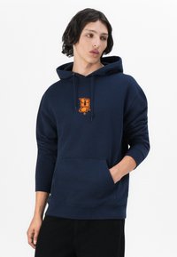 Sweatshirt com capuz azul-marinho feito de tecido suave, apresentando um bolso tipo canguru na frente e um gráfico de logotipo laranja no peito.