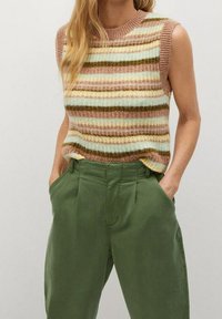 Haut sans manches en tricot avec des rayures horizontales rose, beige, verte et bleu clair, associé à un pantalon vert olive taille haute.