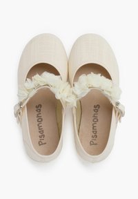 Zapatos Mary Jane de lona beige con acabado texturizado, presentan una correa floral, puntera redonda y una pequeña hebilla plateada.