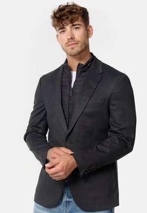 Grau strukturierte Blazer mit einem Ein-Knopf-Verschluss, über einer schwarzen gesteppte Zip-Jacke geschichtet. Verfügt über gekerbte Revers und Kontrastnähte.