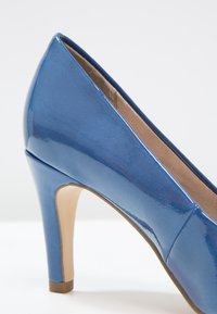 Escarpin à talon haut en cuir verni bleu brillant avec un bout pointu et un talon effilé. Présente une surface lisse et une doublure intérieure de couleur chair.