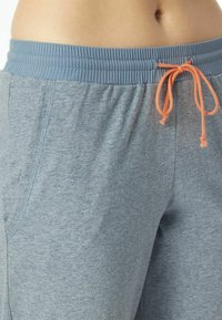 Gray athletic shorts with elastic waistband and adjustable orange drawstring. Features side pockets and a soft, textured fabric.