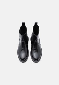 Crne kožne čizme do gležnja s sjajnom završnom obradom, elastičnim bočnim panelima, zaobljenim vrhom i teksturiranom gumenom potplatom. Ravni dizajn, bez vidljivih metalnih dijelova.