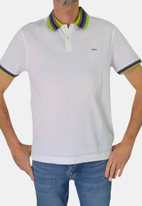 Polo bianco con colletto a righe multicolori in verde, viola e blu. Presenta una patta con tre bottoni e un piccolo logo blu.