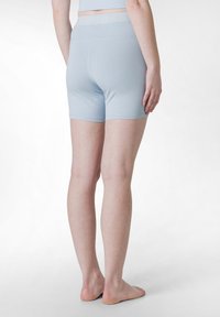 Ljusblå, stretchiga sportshorts med elastisk midja, med en slät yta och en figurnära design, visade från baksidan.