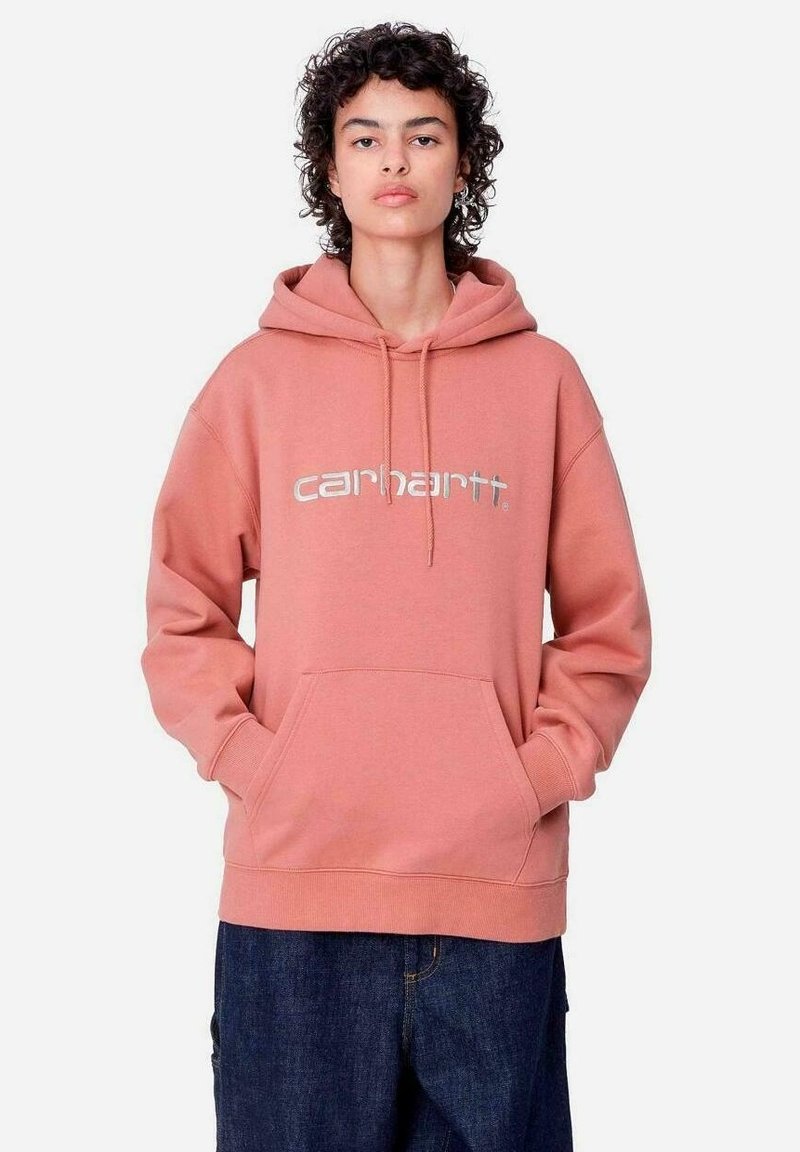 Sudadera de forro polar rosa con un gran bolsillo frontal, capucha con cordón y logo plateado de "Carhartt". Presenta puños y dobladillo acanalados.