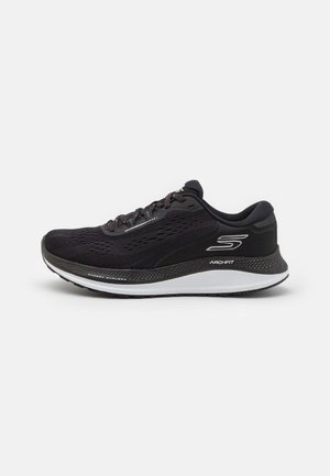 Sort Skechers Arch Fit løbesko med mesh-overdel, hvid sål og logo på siden, vist fra ydersiden mod en hvid baggrund.