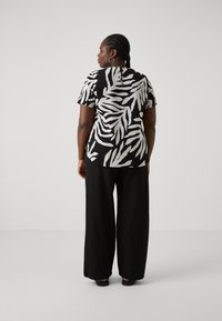 Black and white leaf-patterned shirt with a round neckline and short sleeves, paired with loose black trousers. Smooth texture, relaxed fit.
