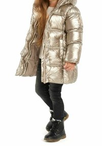 Kurtka puchowa w metalicznej złotej barwie z kapturem, zamkiem z przodu i zatrzaskami. Połączona z czarnymi obcisłymi dżinsami i czarnymi lace-up butami z futrzanym wykończeniem.