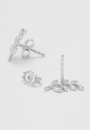 Srebrne kolczyki wkrętki w kształcie małych gałązek oliwnych z zapięciami na motylki na białej powierzchni.