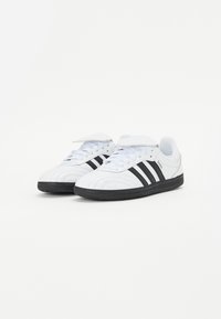 Hvit sneakers med svarte striper, skinnoverdel, rund tå, teksturert gummisåle, snøring og polstret tunge.