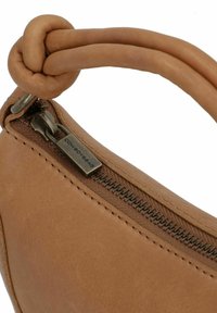 Bruine leren tas met een ritssluiting, voorzien van een gedraaide handgreep en zichtbare stiksels in de buurt van het ritsgebied.