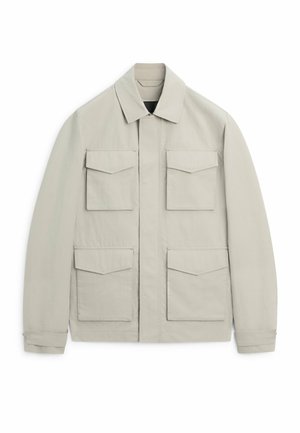 Hellbeige Jacke mit spitzem Kragen, vier vorderen Klappentaschen, langen Ärmeln und einem verdeckten Frontreißverschluss.