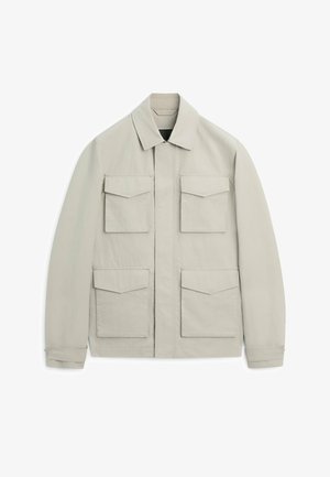 Hellbeige Jacke mit spitzem Kragen, vier vorderen Klappentaschen, langen Ärmeln und einem verdeckten Frontreißverschluss.