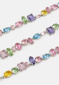 Multicolored gemstone bracelet with pear, oval, and rectangular shapes in pink, blue, green, yellow, and purple, set in silver-toned metal.