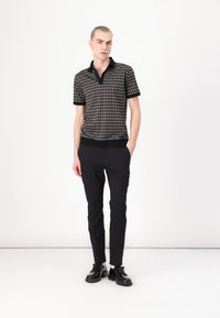 Mustri musta ja hall houndstooth polo särk musta krae ja varrukatega, kombineeritud slim-fit mustade pükste ja mustade lipsudega kingadega.
